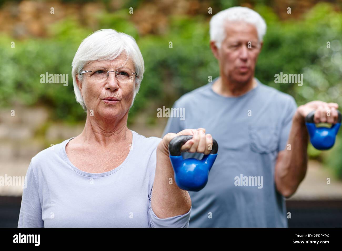 Ein Seniorenpaar trainiert mit leichten Gewichten im Freien. Stockfoto