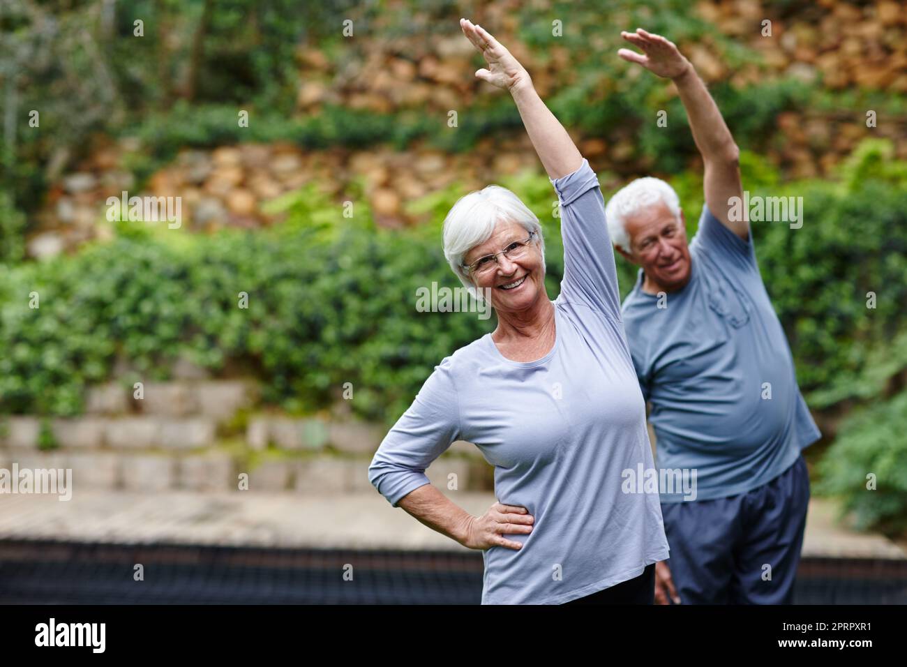 Es ist wichtig, in Ihrem Alter aktiv zu bleiben. Ein Seniorenpaar macht gemeinsam Yoga im Freien. Stockfoto