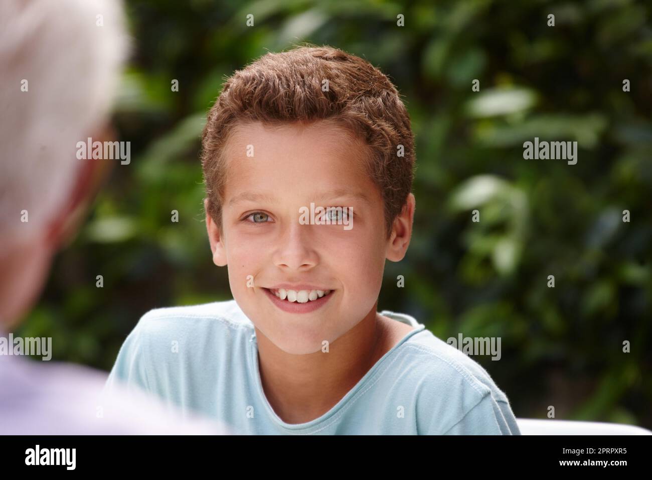 Hes ein tolles Kind. Porträt eines glücklichen kleinen Jungen, der mit seiner Familie draußen sitzt. Stockfoto