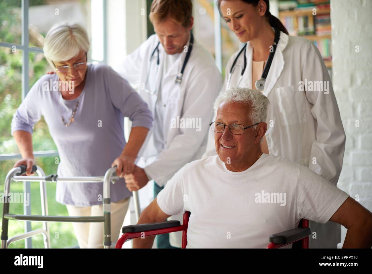 Die beste Betreuung. Zwei ältere Menschen werden vom Pflegepersonal unterstützt. Stockfoto