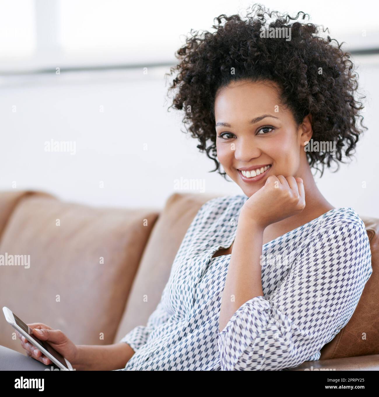 Nirgendwo entspannender als zu Hause. Porträt einer attraktiven Frau, die mit ihrem Smartphone auf dem Sofa sitzt. Stockfoto