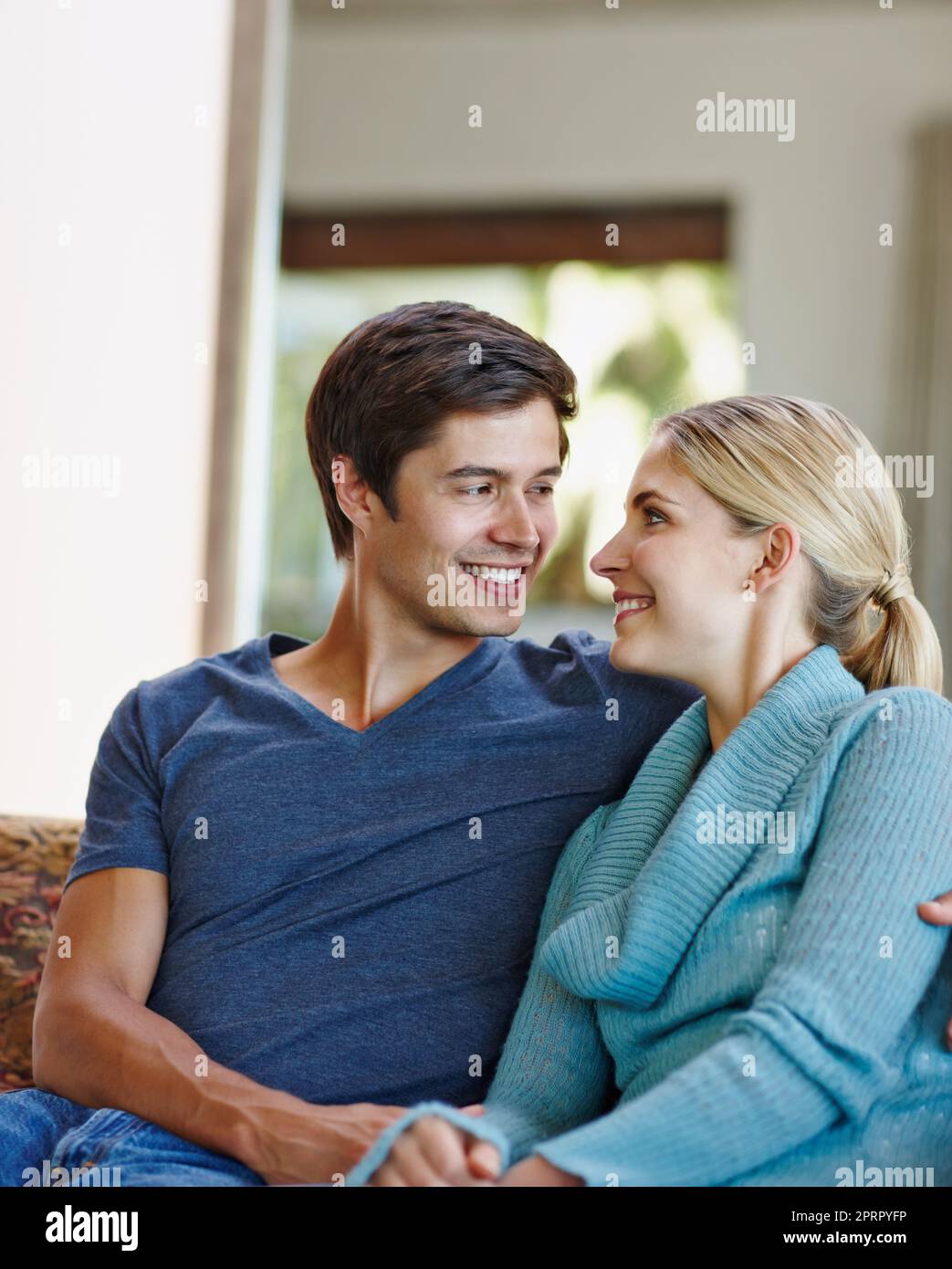 Sie setzen Herz in unser Zuhause. Ein glückliches junges Paar, das sich zu Hause auf dem Sofa entspannt. Stockfoto
