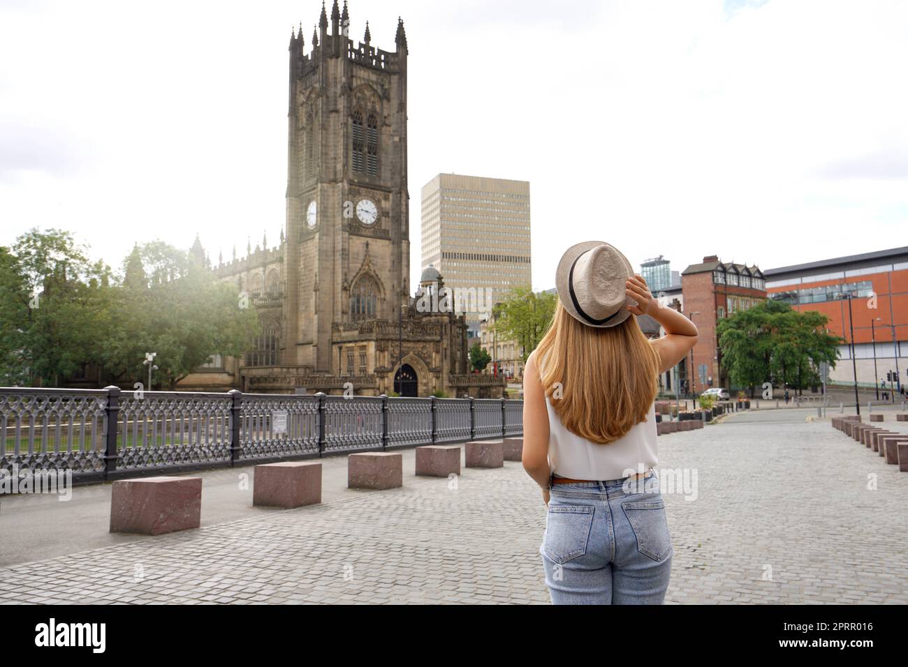 Rückansicht des schönen blonden Mädchens mit Hut zu Fuß in Manchester Stadt an sonnigen Tag, England, Vereinigtes Königreich Stockfoto
