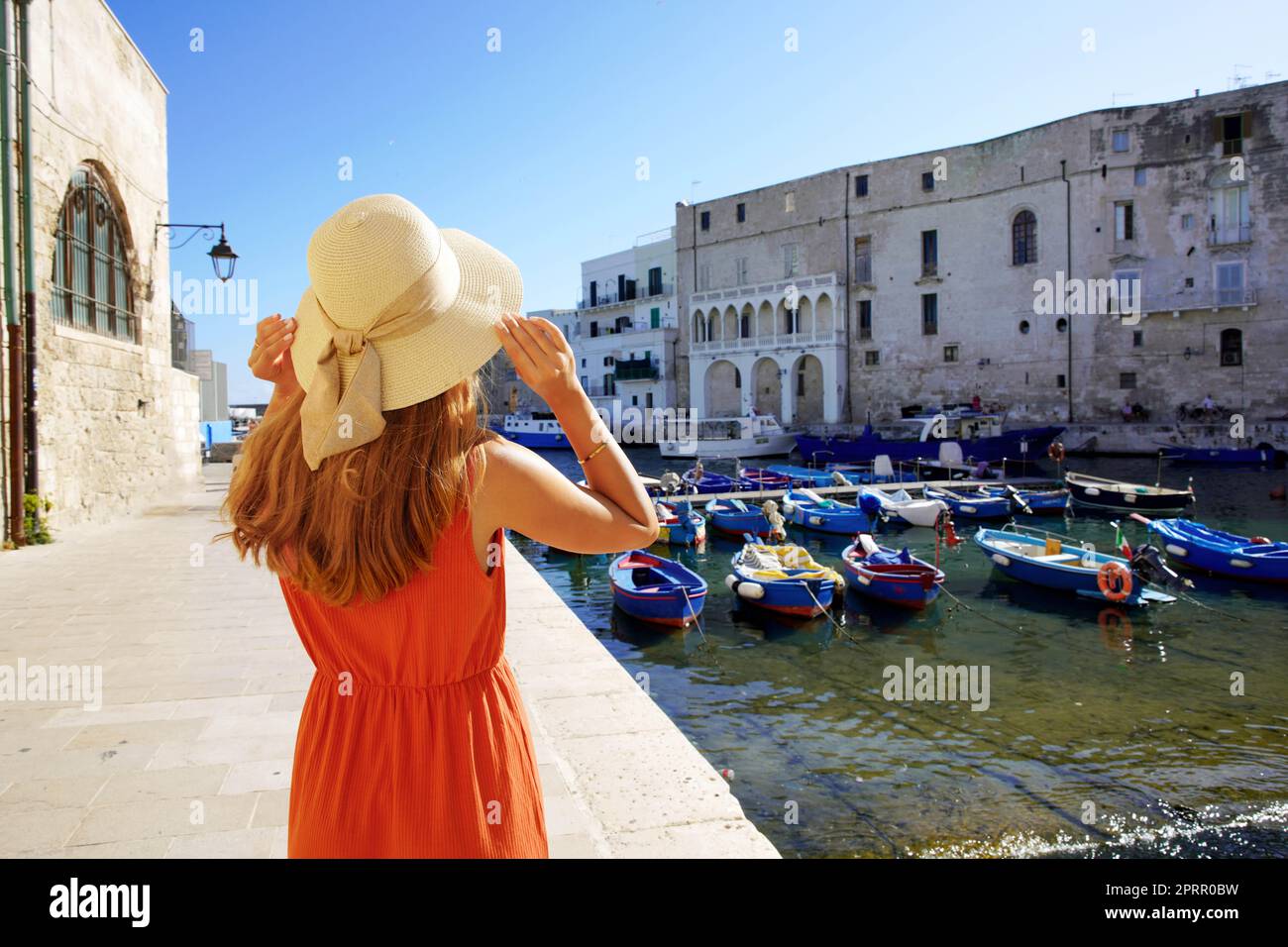 Tourismus in Apulien, Italien. Rückansicht der schönen Mode Mädchen genießen Blick auf Monopoli alten Hafen in Apulien, Italien. Urlaub Europe im Sommer. Stockfoto