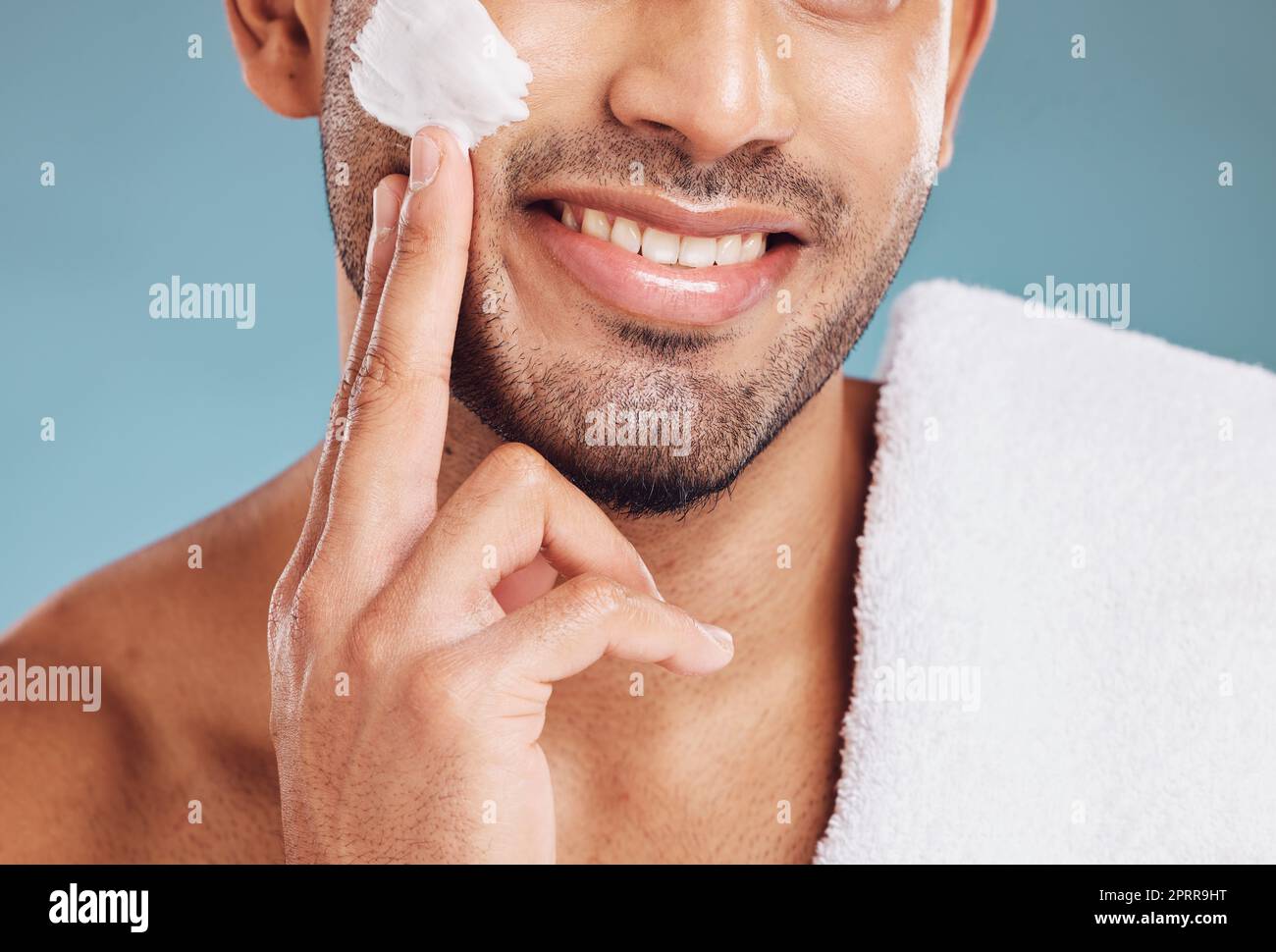 Mann mit Rasiercreme im Gesicht, Hautpflege mit luxuriösem Schönheitsprodukt oder sauberem Gesichtshaar auf blauem Studiohintergrund. Tragen Sie Sonnencreme-Lotion auf den Körper auf, ma Stockfoto
