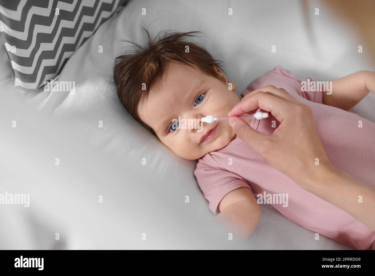 Mutter putzt die Nase ihres Babys mit Wattestäbchen auf dem Bett,  Nahaufnahme Stockfotografie - Alamy