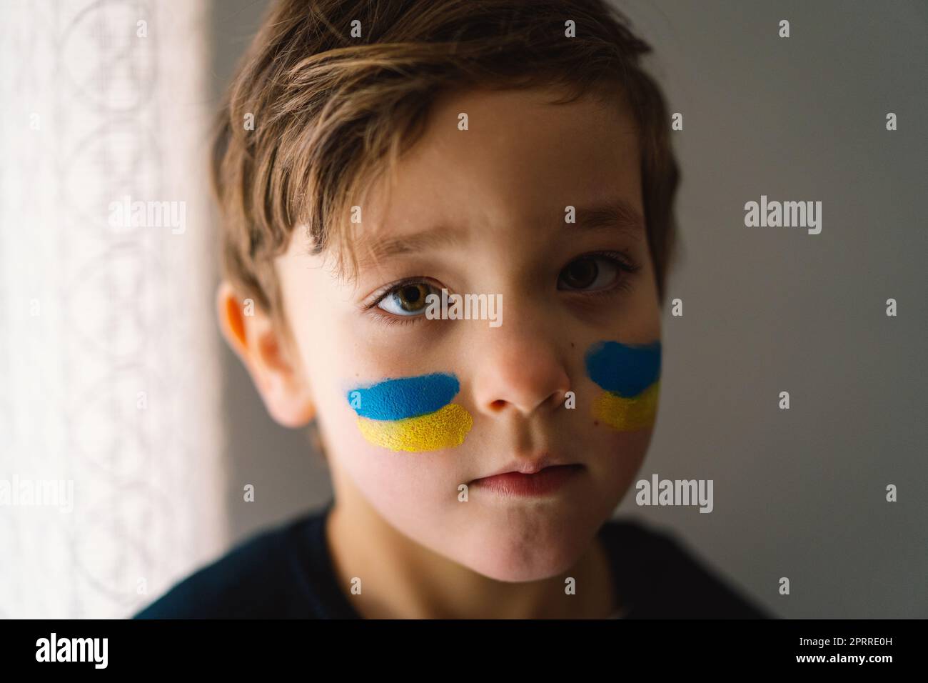 Porträt eines ukrainischen Jungen mit einem Gesicht in den Farben der ukrainischen Flagge. Stockfoto