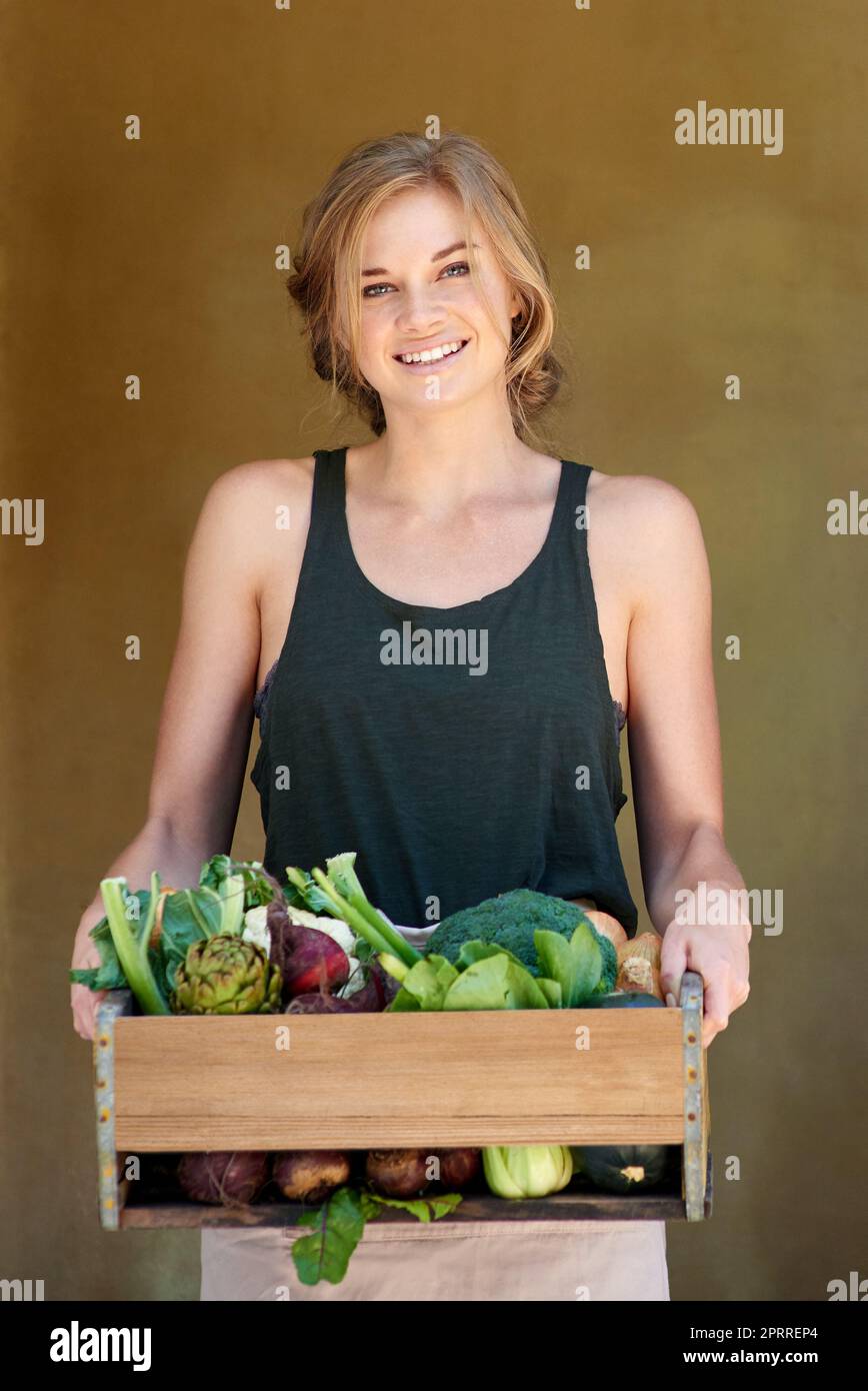 Wachsen Sie das gute Leben. Eine junge Frau, die eine Kiste mit Gemüse im Freien hält. Stockfoto