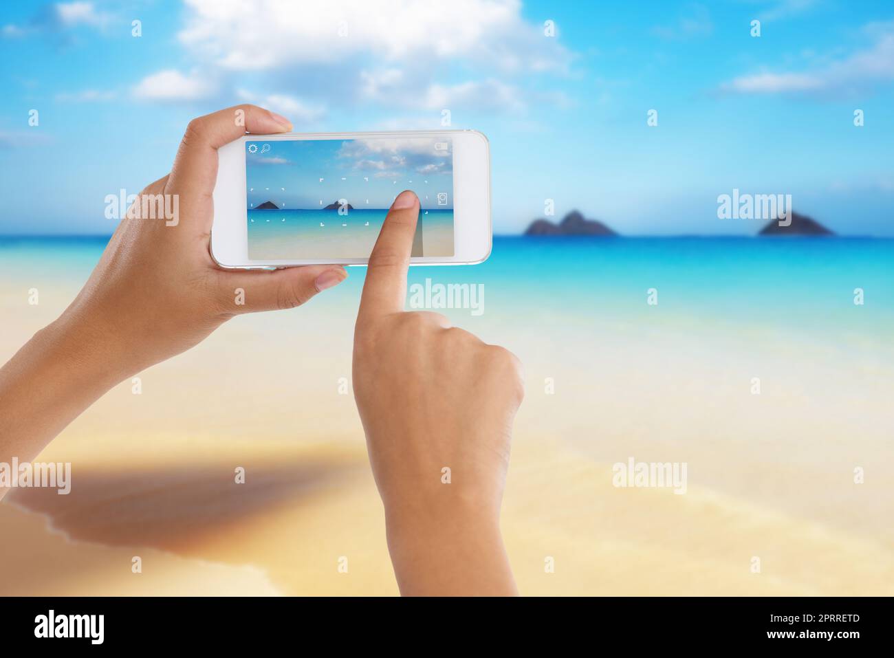 Das perfekte Urlaubsziel. Eine Frau, die mit ihrem Kameratelefon ein Foto von einem wunderschönen Meerblick fotografiert. Stockfoto