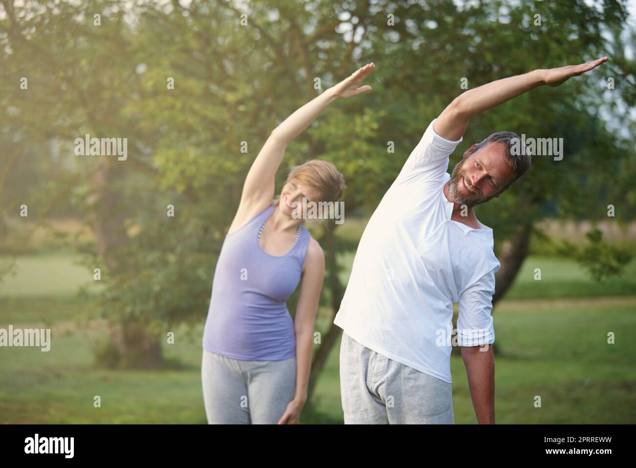 Ihr Training der Wahl. Ein glückliches reifes Paar, das Yoga in der Natur macht. Stockfoto