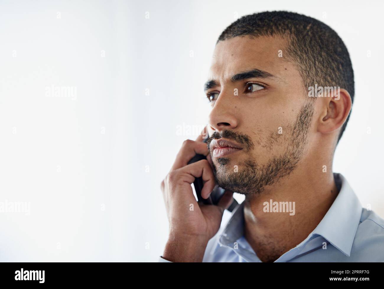 Ernsthafte Geschäftsgespräche. Ein hübscher junger Geschäftsmann, der im Büro Handy benutzt. Stockfoto