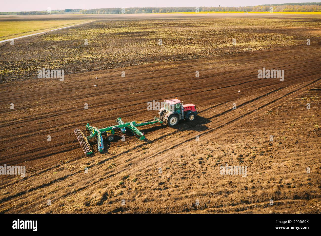 Luftaufnahme. Feld Für Das Pflügen Des Traktors. Beginn Der Landwirtschaftlichen Frühjahrssaison. Grubber gezogen von EINEM Traktor auf dem Land ländliche Feldlandschaft Stockfoto