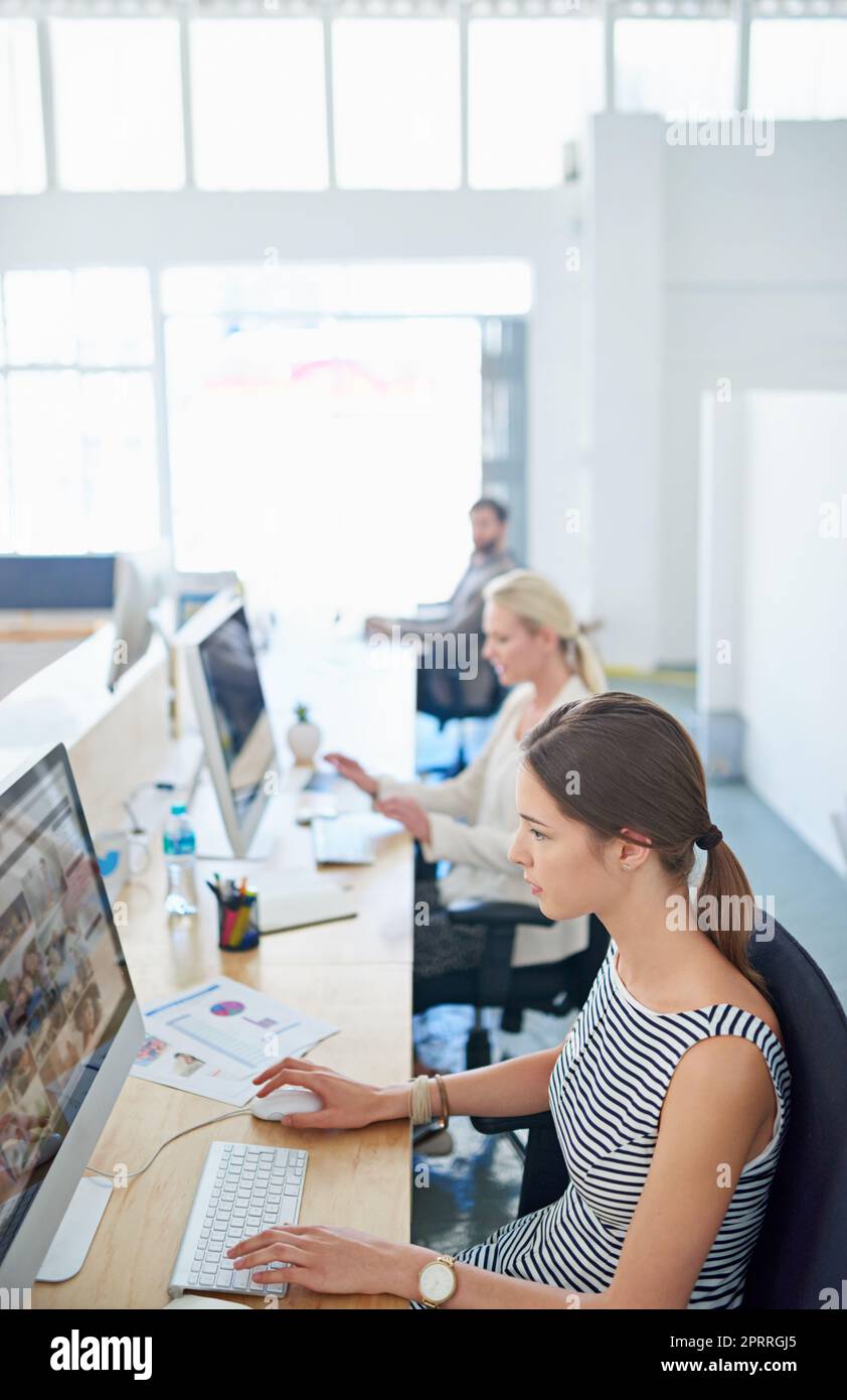 Harte Arbeit an dem neuesten Projekt. Eine junge Büroangestellte, die an ihrem Arbeitsplatz in einem Büro sitzt. Stockfoto