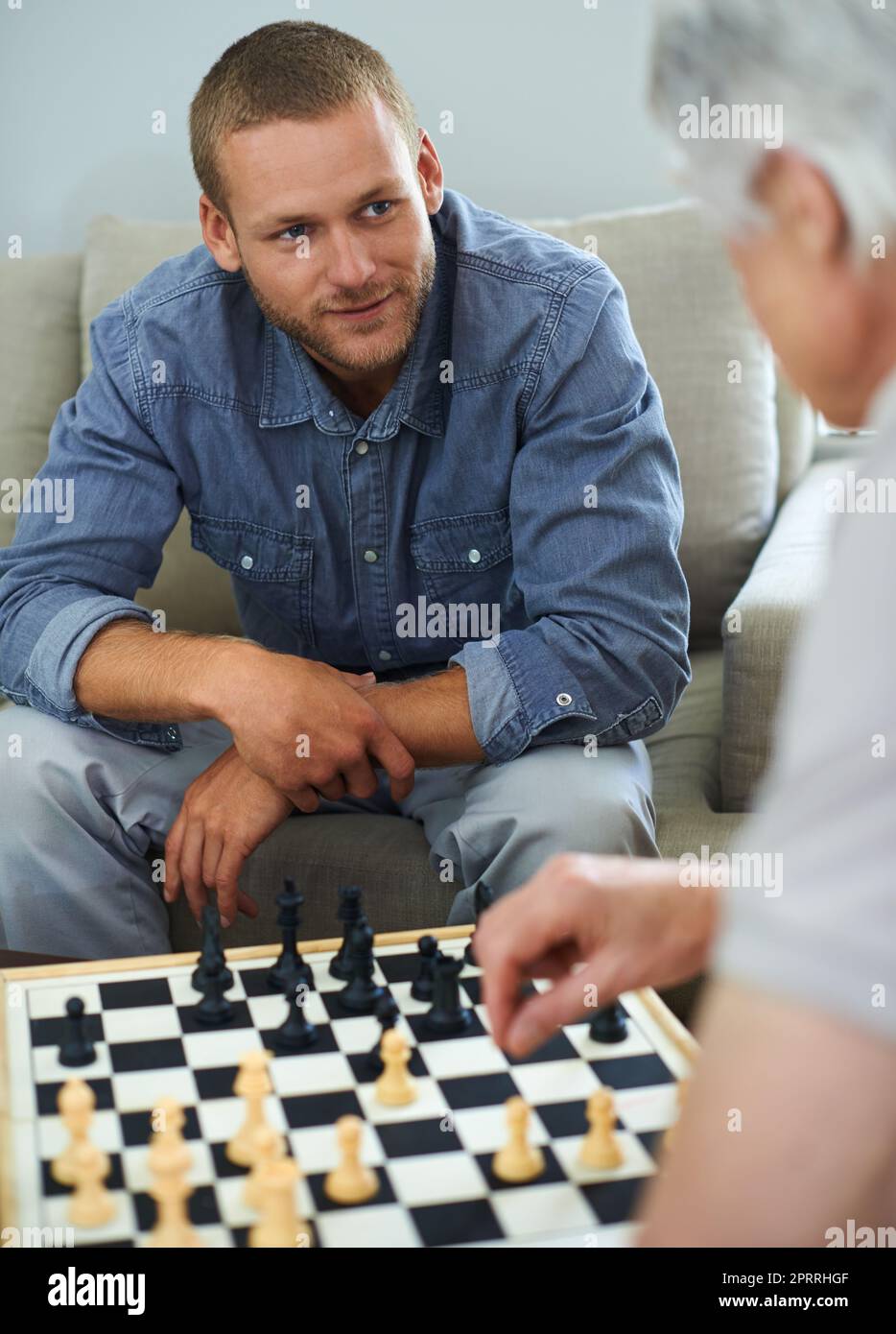 Wie hat er das gemacht? Ein Vater und ein Sohn spielen zu Hause gemeinsam eine Partie Schach. Stockfoto