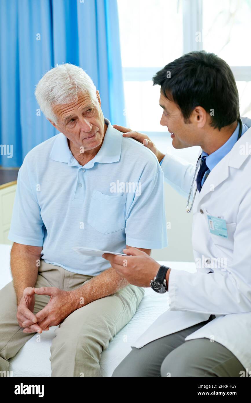 Keine Sorge, seine gute Nachricht. Ein hübscher junger Arzt liefert Nachrichten an einen älteren Patienten. Stockfoto