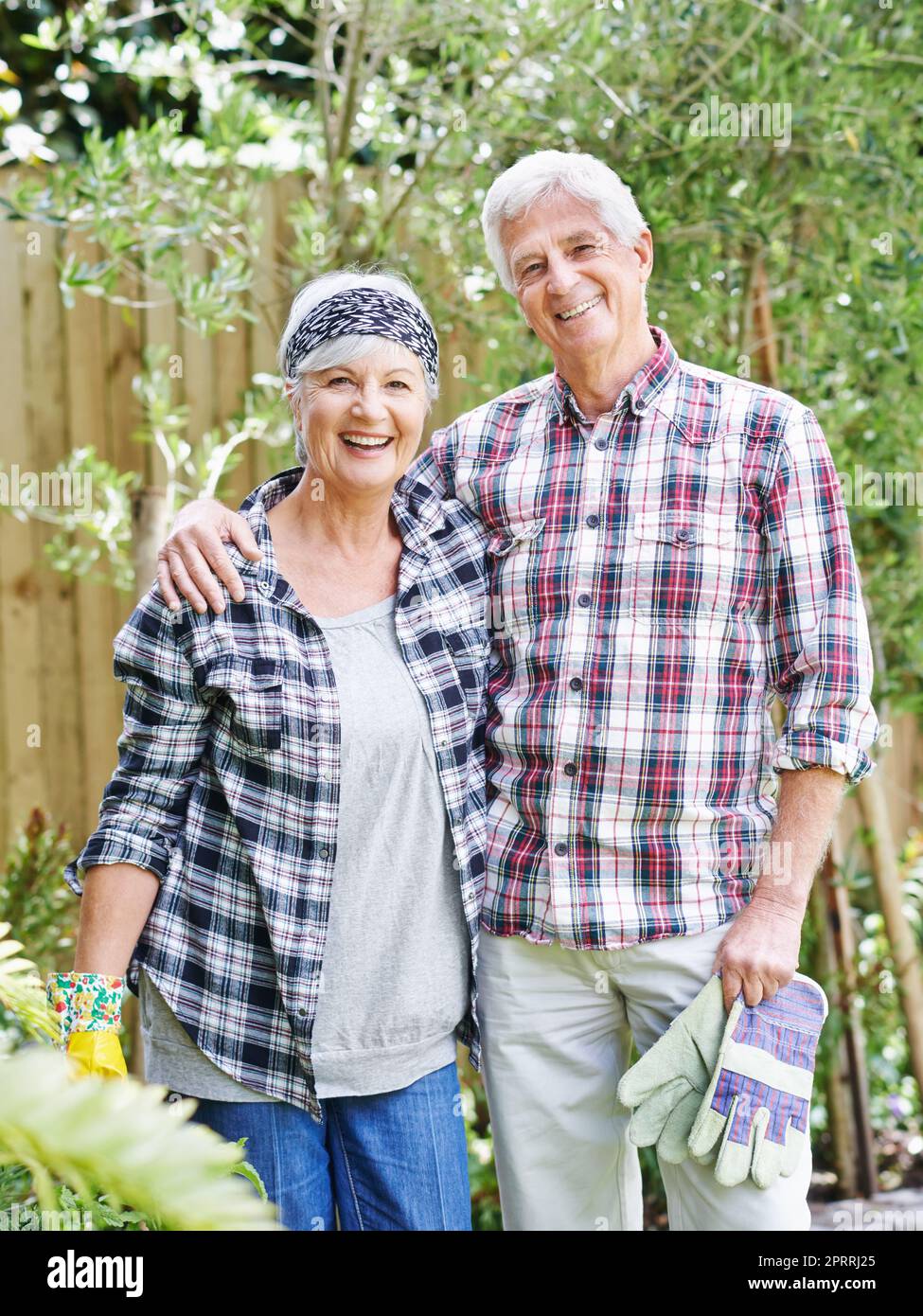 Unser Garten ist der Neid der Nachbarschaft. Ein glückliches Seniorenpaar beschäftigt Gartenarbeit in ihrem Hinterhof. Stockfoto