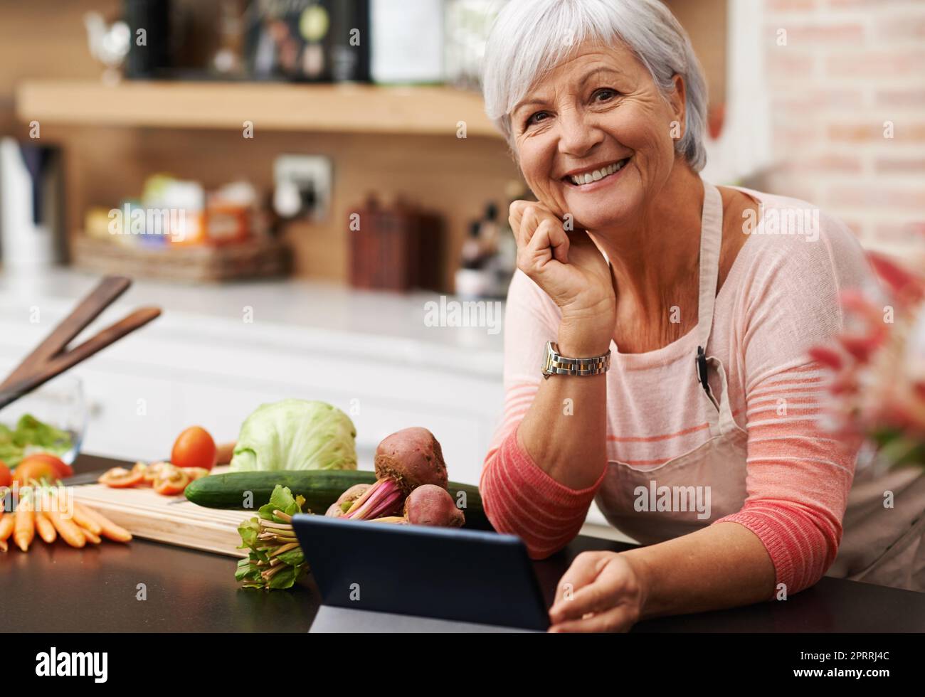 Ich würde gerne meine Rezepte mit Ihnen teilen. Eine Frau posiert gemütlich in ihrer Küche. Stockfoto