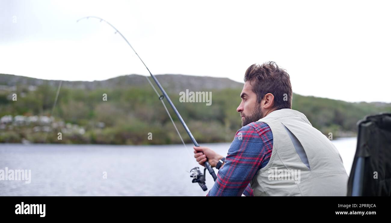 Fisch Vorsicht ... ein schöner Mann Angeln an einem natürlichen See. Stockfoto