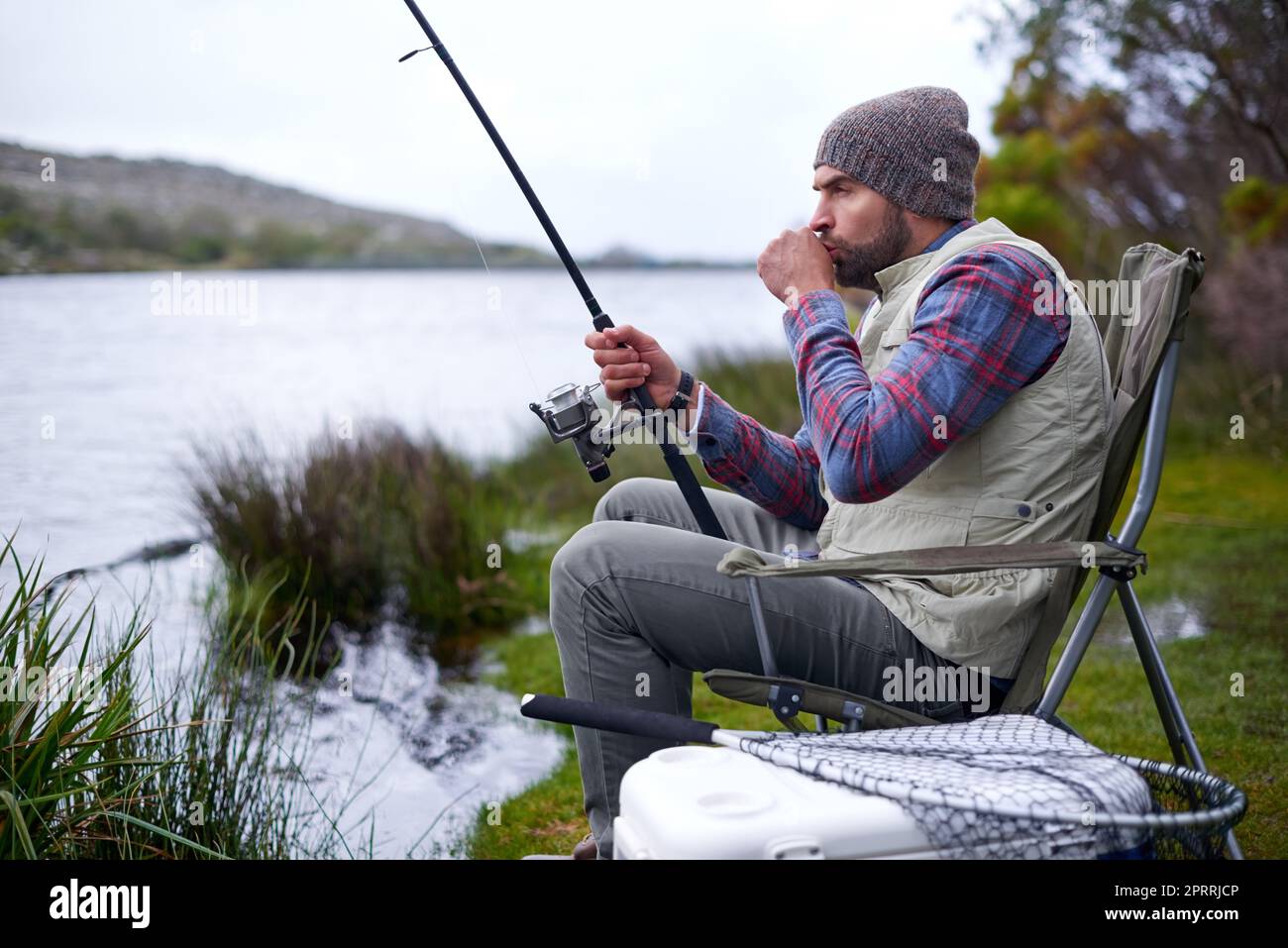 Es geht um Geduld. Ein gutaussehender Mann, der an einem natürlichen See angeln kann. Stockfoto