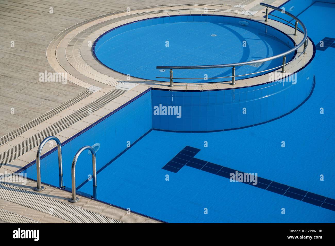 Blick von oben auf den Pool mit blauem Wasser und Eingang mit Haltegriffen aus Chrom Stockfoto