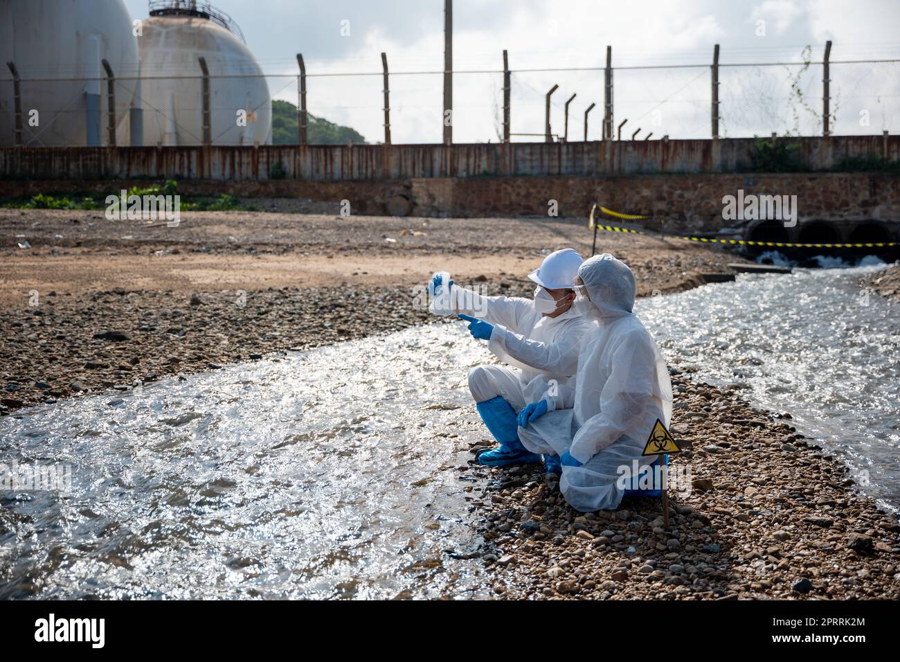 Ökologe entnehmen wassertoxische Chemikalien aus dem Fluss mit Reagenzglas und weisen weißen Rauch auf Stockfoto