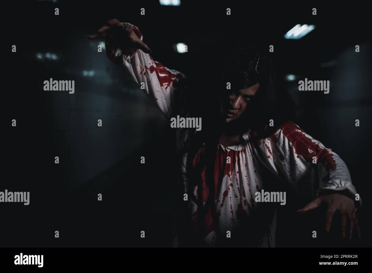 Horror, blutrünstige Geistermädchen-Haare, die Gesicht und Augen mit ausgestrecktem Arm bedecken Stockfoto