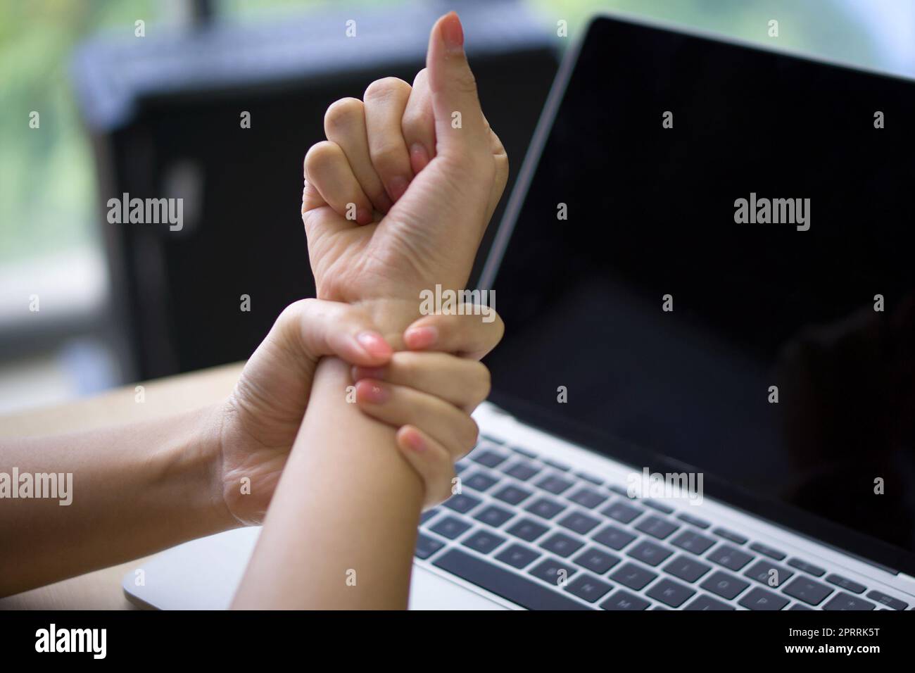 Eine junge Frau verletzte sich lange Zeit am Handgelenk, weil sie einen Laptop benutzte. Nahaufnahme Stockfoto