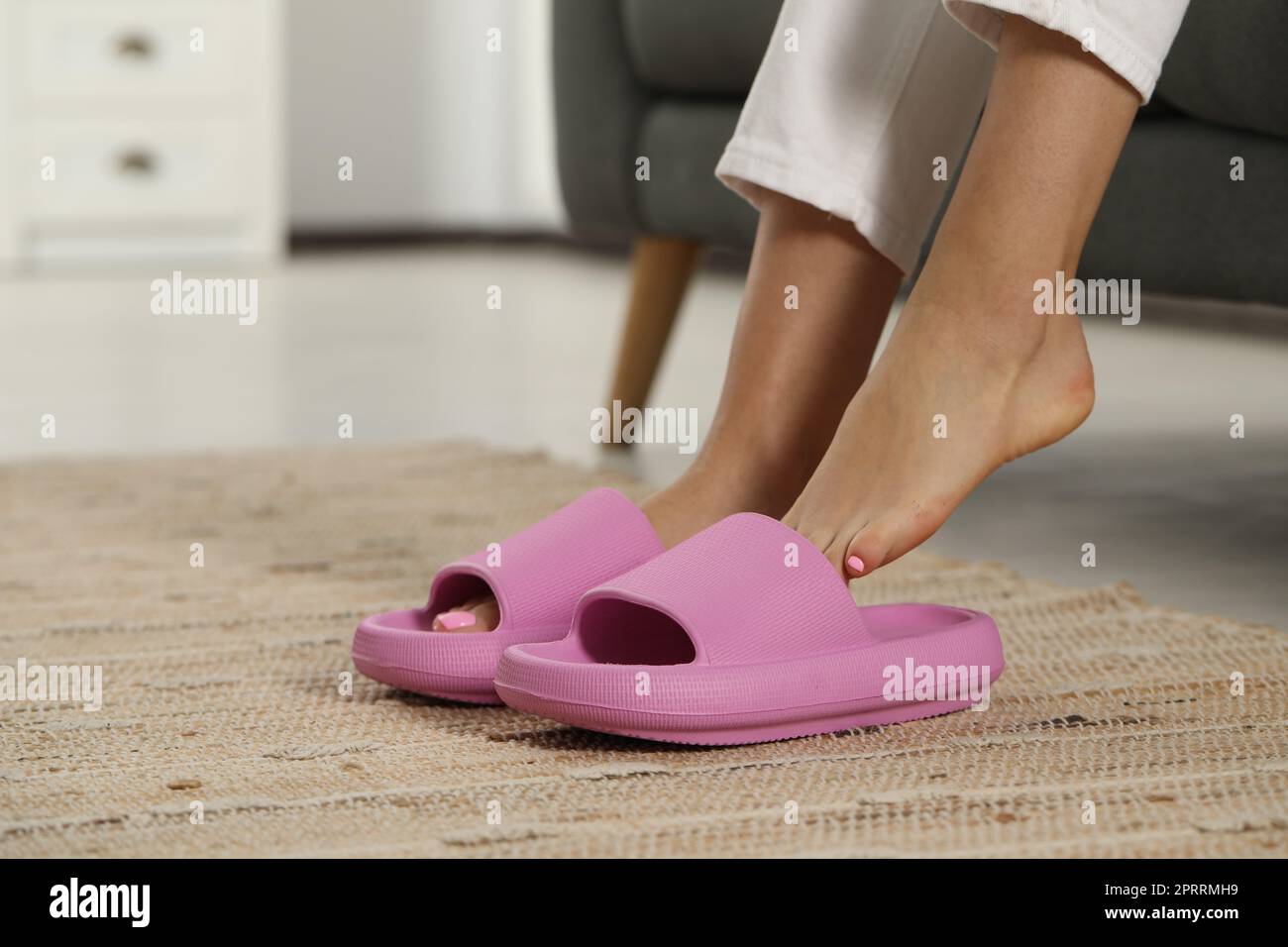 Eine Frau, die drinnen pinkfarbene Pantoffeln anzieht, Nahaufnahme Stockfoto
