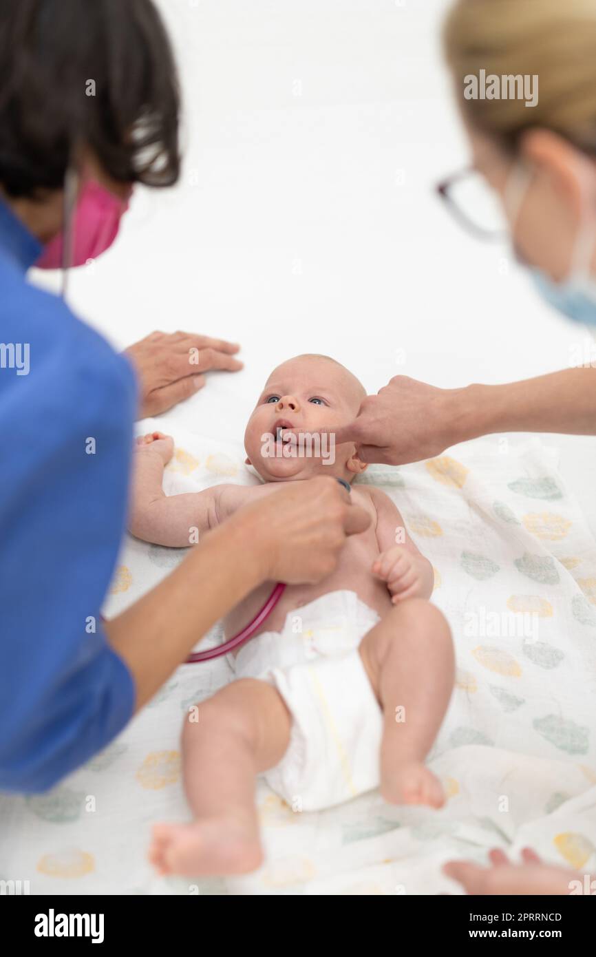 Baby liegt auf dem Rücken, als sein Arzt ihn untersucht Bei einer Standarduntersuchung Stockfoto
