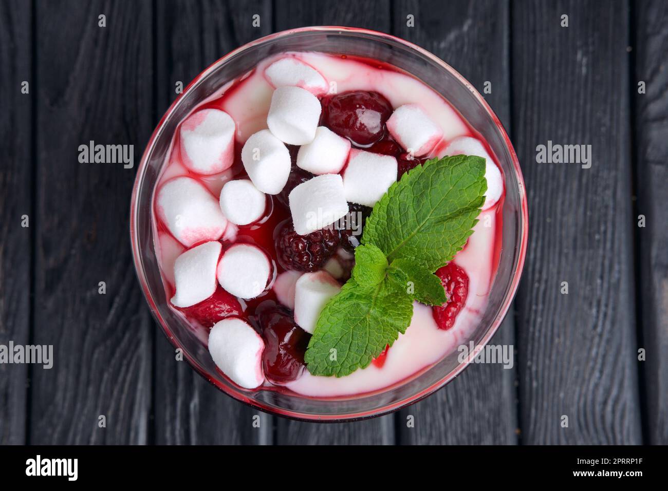 Ein Glas Joghurt mit Marshmallow und Himbeeren, dekoriert mit Minzblättern. Draufsicht. Stockfoto