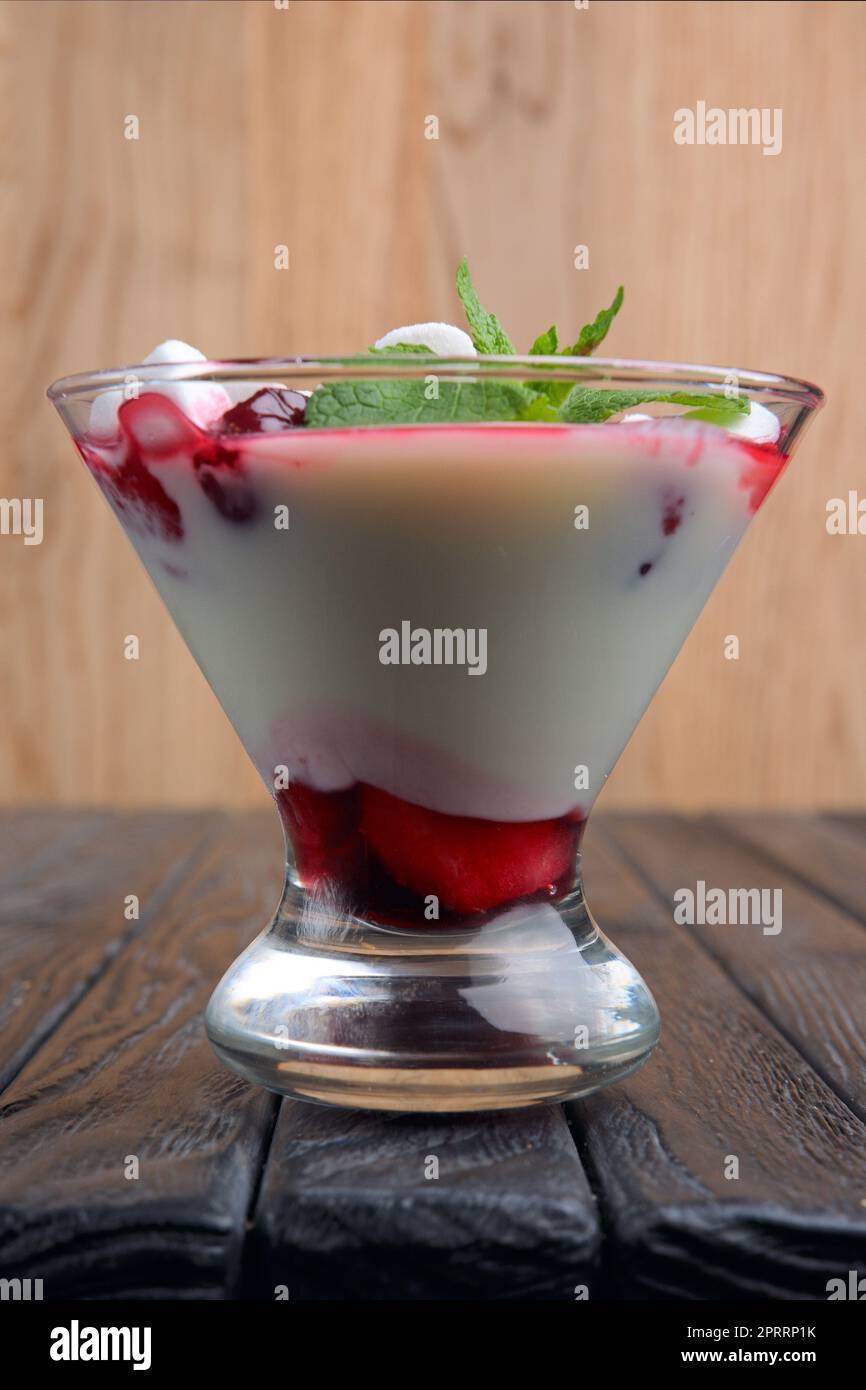 Ein Glas Joghurt mit Marshmallow und Himbeeren, dekoriert mit Minzblättern. Stockfoto