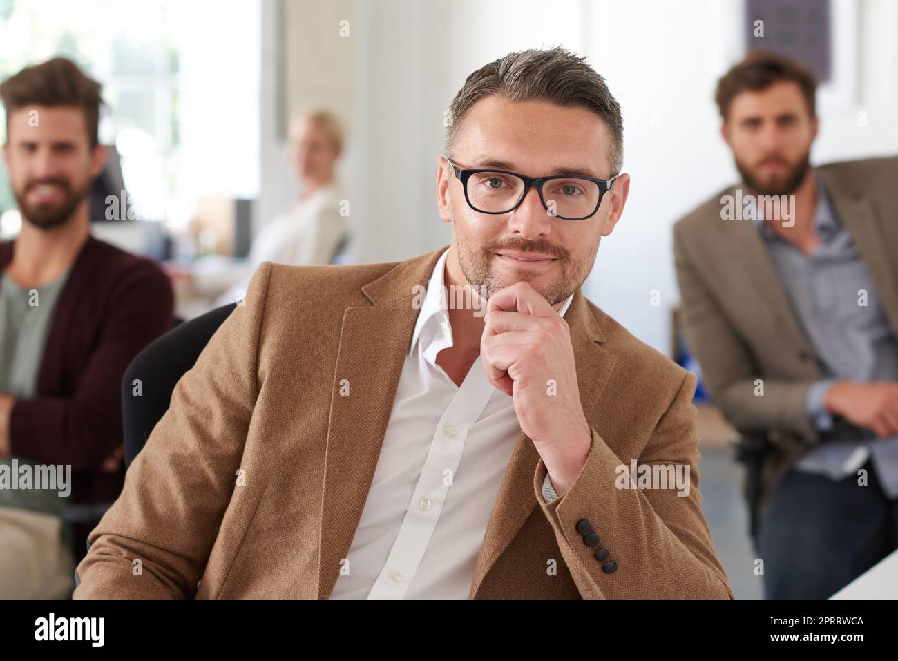 Anführer, dem Ihr vertrauen könnt. Ein positiver reifer Designer lächelt in einem gemeinsamen Büro an der Kamera. Stockfoto