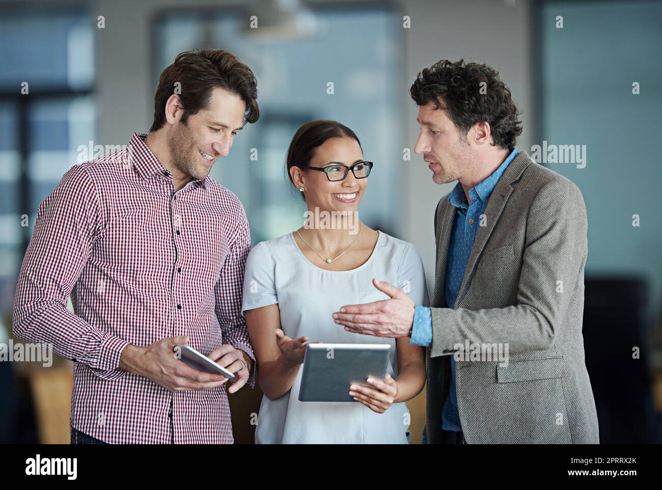 Umsetzung ihrer Pläne. Eine Gruppe von Mitarbeitern, die in einem Büro stehen und über ein digitales Tablet reden. Stockfoto