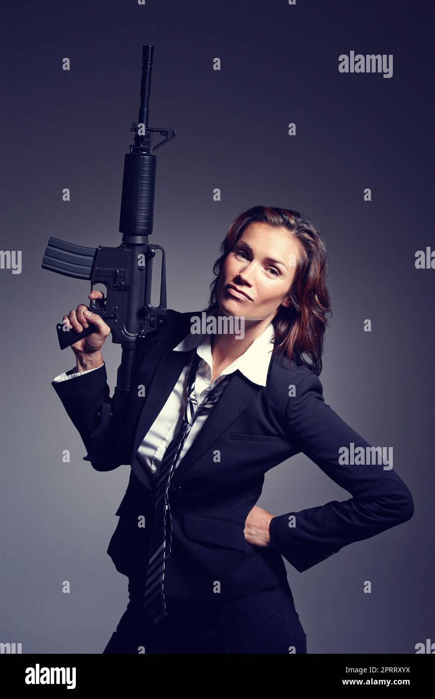 Bringen Sie die großen Waffen heraus. Eine junge Geschäftsfrau in Anzug und Krawatte mit Gewehr. Stockfoto