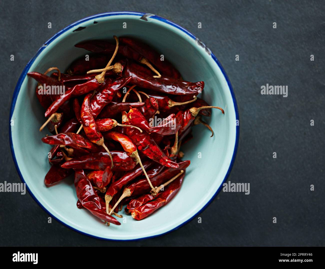 Intensiver Geschmack. In einer Schüssel auf einem Küchentischtisch wurden getrocknete rote Chilischoten aus einem hohen Winkel geschossen. Stockfoto