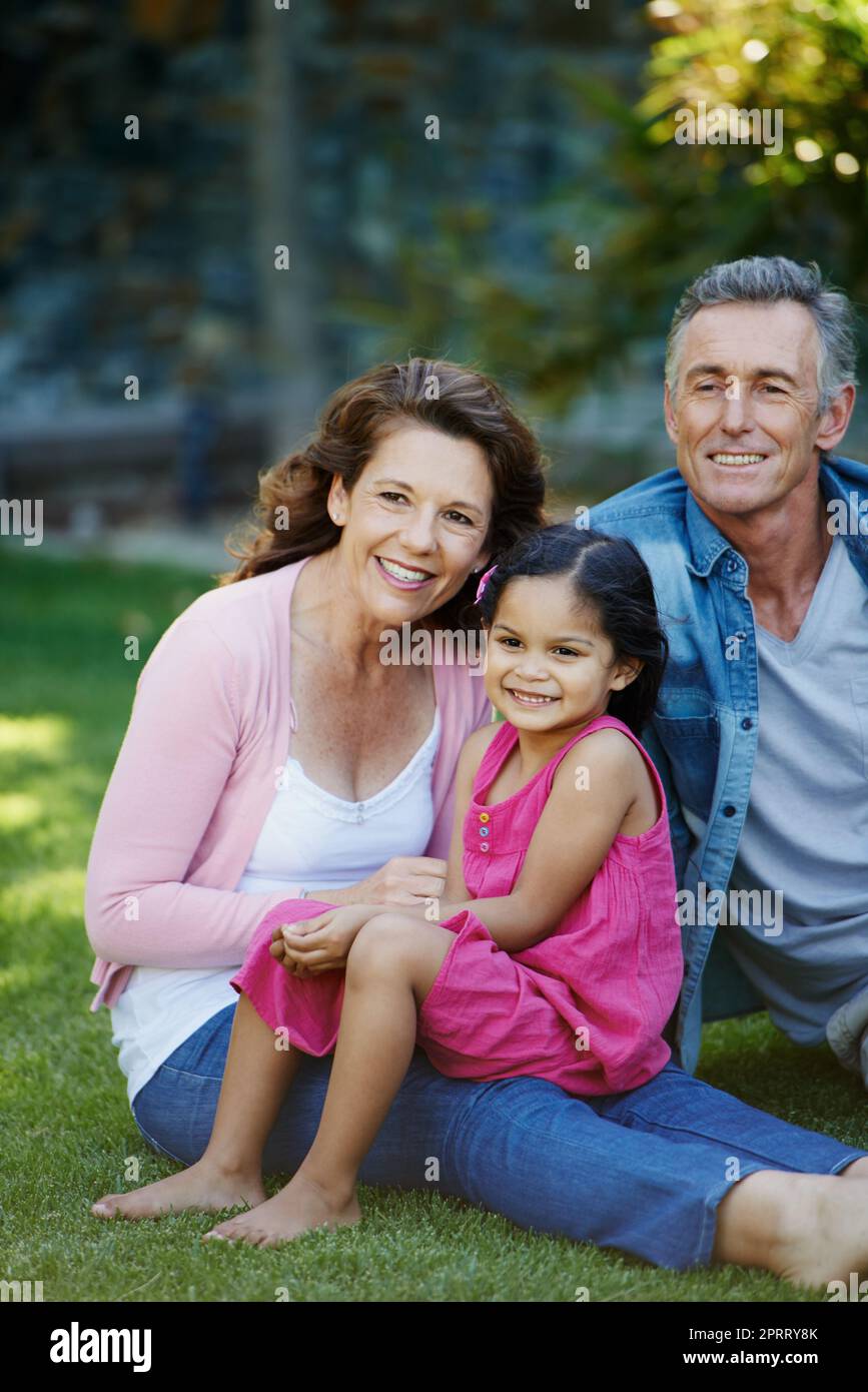 Ein älterer Mann und eine ältere Frau genießen einige Zeit mit ihrer Enkelin im Freien. Stockfoto