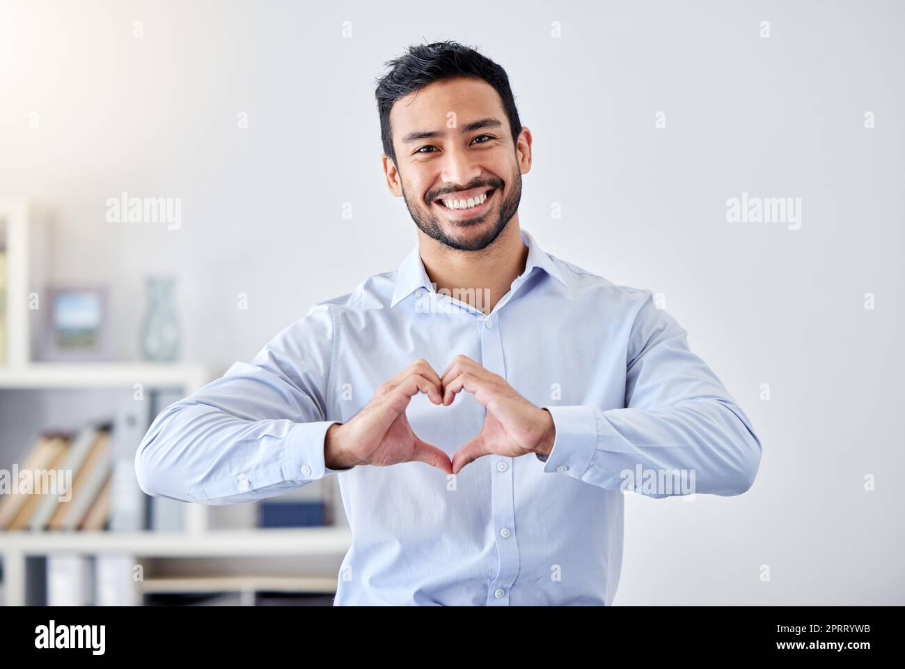 Asiatischer Geschäftsmann, Herzzeichen- und Handgesten-Emoji für Unterstützung, Vertrauen und Leidenschaft für Erfolg. Porträt eines Lächelns, glücklichen oder motivierenden Mitarbeiters für wohltätige Zwecke, Gemeindeliebe oder Hilfe für Mitarbeiter im Amt Stockfoto