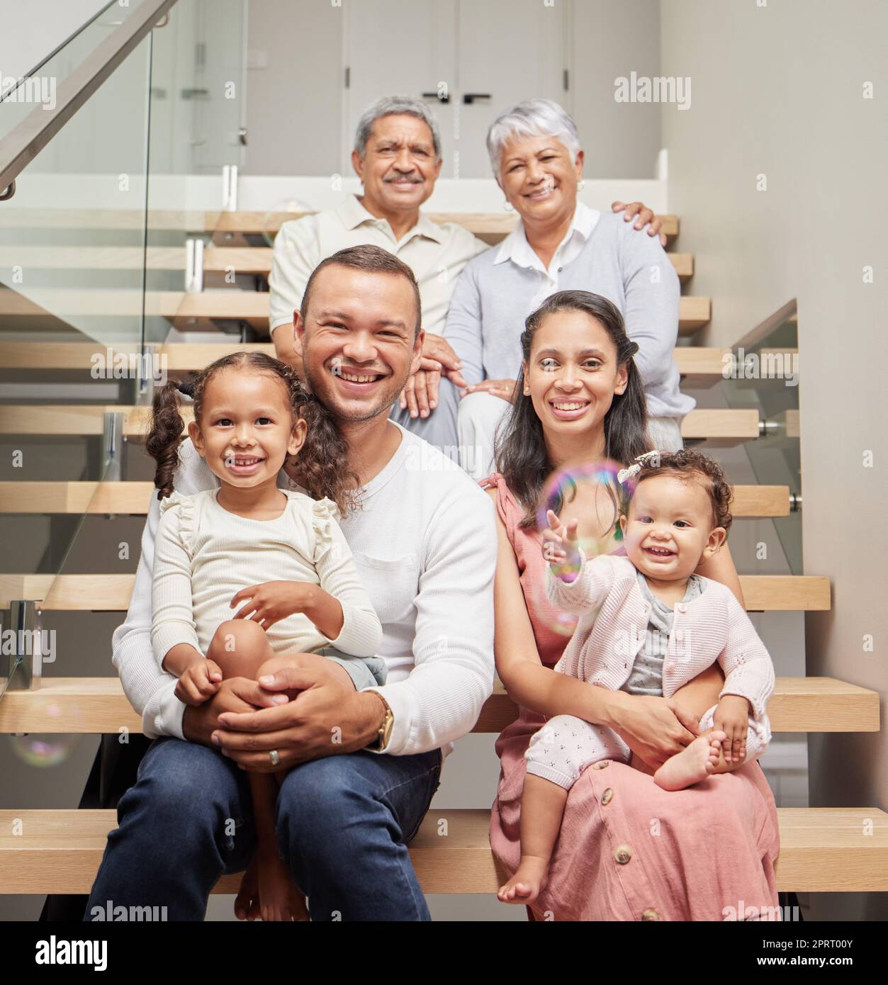 Große Familie, drei Generationen und das Glück von Kindern, Eltern und Großeltern, die zusammen auf der Treppe in ihrem Zuhause sitzen und lächeln. Bindung, Unterstützung und Nähe von Kindern zu Mann und Frau Stockfoto