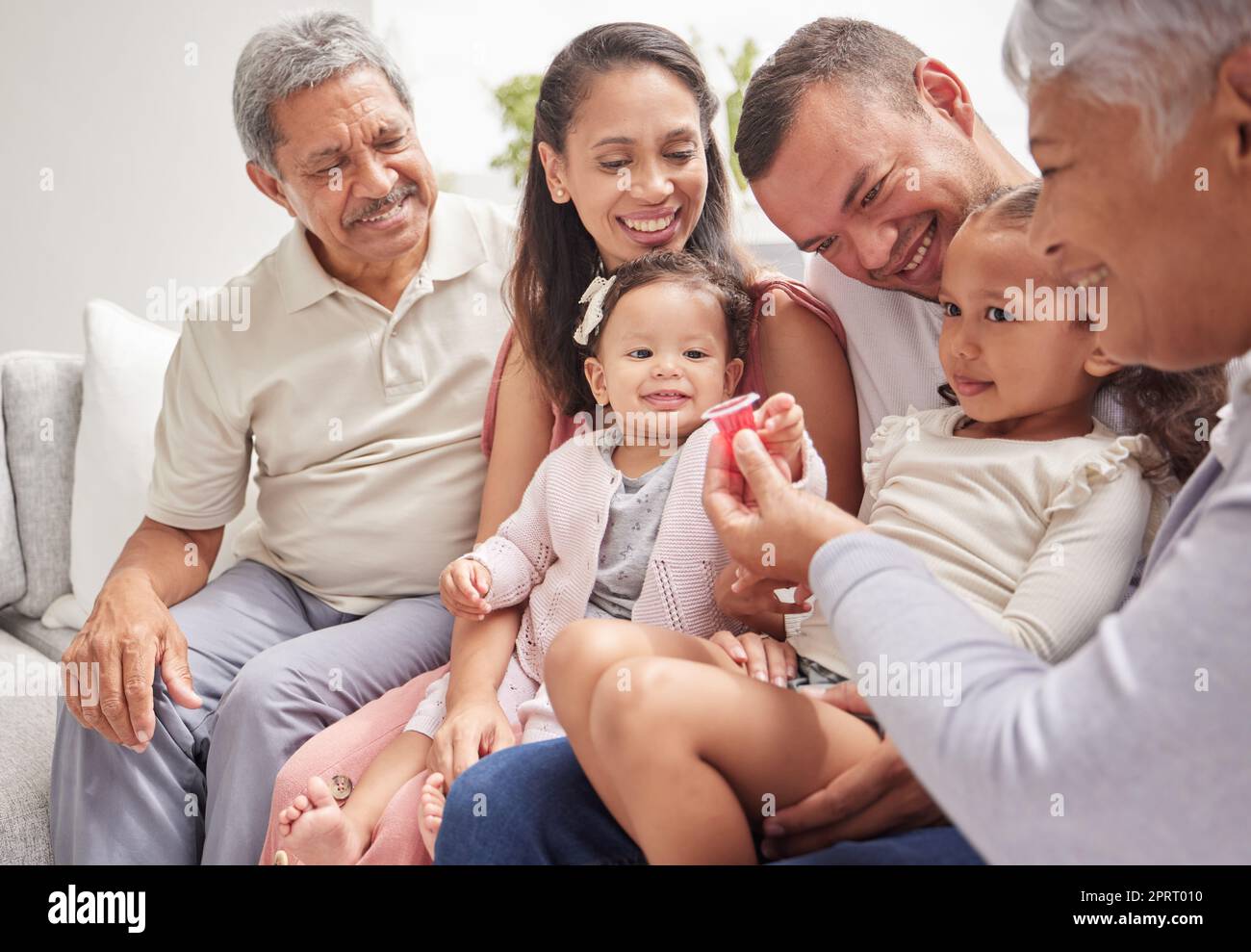 Familie, Liebe und Kinder mit Großeltern und Kindern auf einem Sofa im Wohnzimmer während eines Besuchs zu Hause. Glücklich, lächelnd und Beziehung mit einem Mann, einer Frau und Verwandten, die zusammen in einem Haus sitzen Stockfoto
