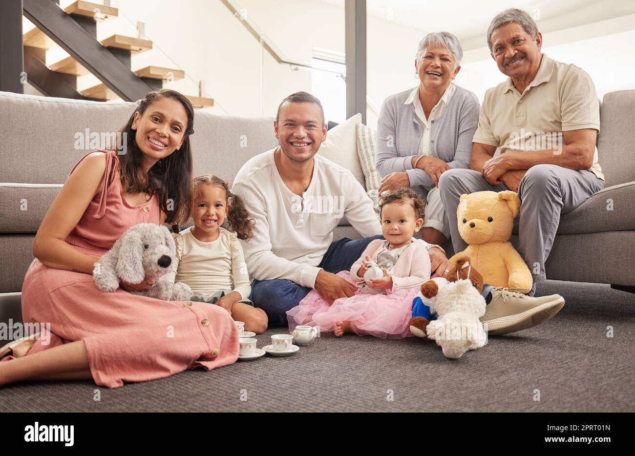 Porträt einer glücklichen Familie, die zusammen eine Teeparty im Wohnzimmer veranstaltet, lächelt und sich auf dem Boden entspannt. Fröhliche Großeltern genießen das Wochenende mit ihrem Enkel, sind verspielt und haben Spaß Stockfoto