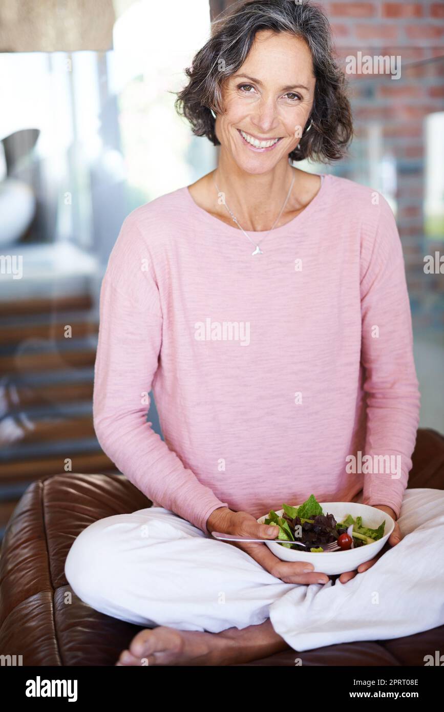 Ein langes Leben durch gesundes Leben genießen. Porträt einer reifen Frau, die einen Salat isst. Stockfoto