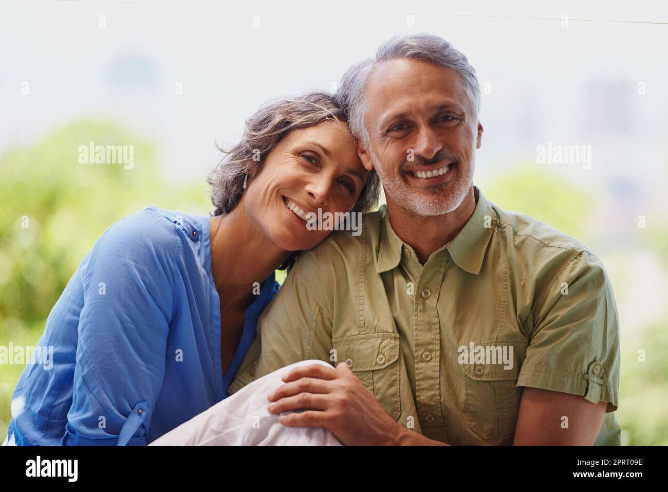 Sie passen perfekt zusammen. Ein beschnittenes Porträt eines glücklichen, mittleren Erwachsenen-Paares, das an einem sonnigen Tag draußen sitzt. Stockfoto