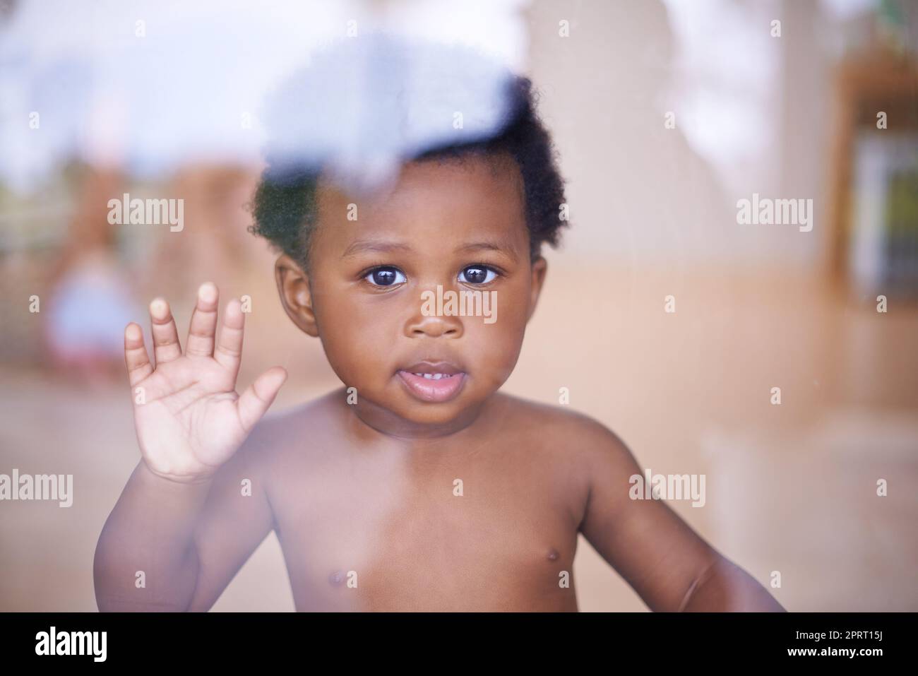 Bereit, die Welt kennenzulernen. Porträt eines niedlichen Jungen, der durch das Fenster schaut. Stockfoto