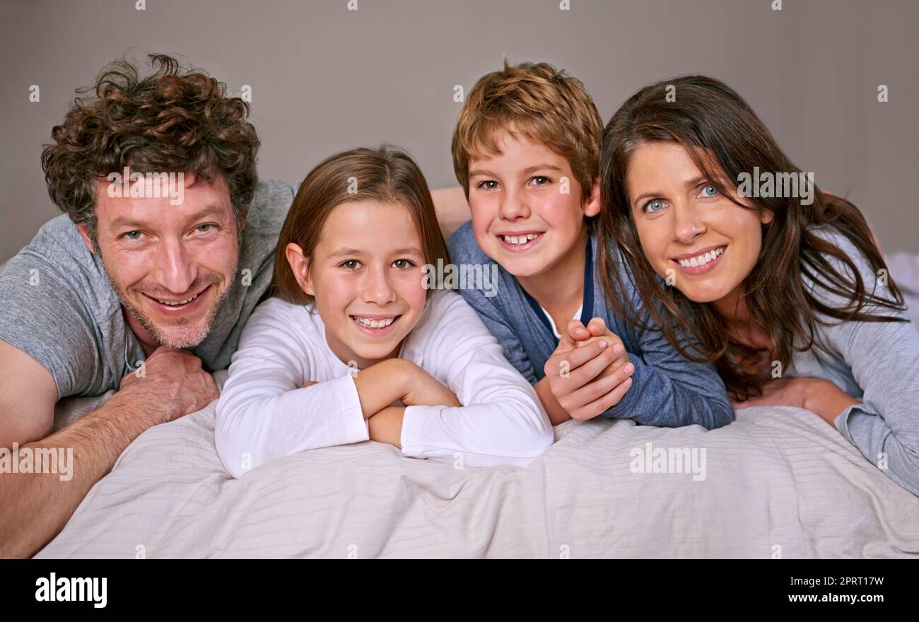 Eine große glückliche Familie. Porträt einer glücklichen vierköpfigen Familie, die zusammen auf einem Bett liegt. Stockfoto