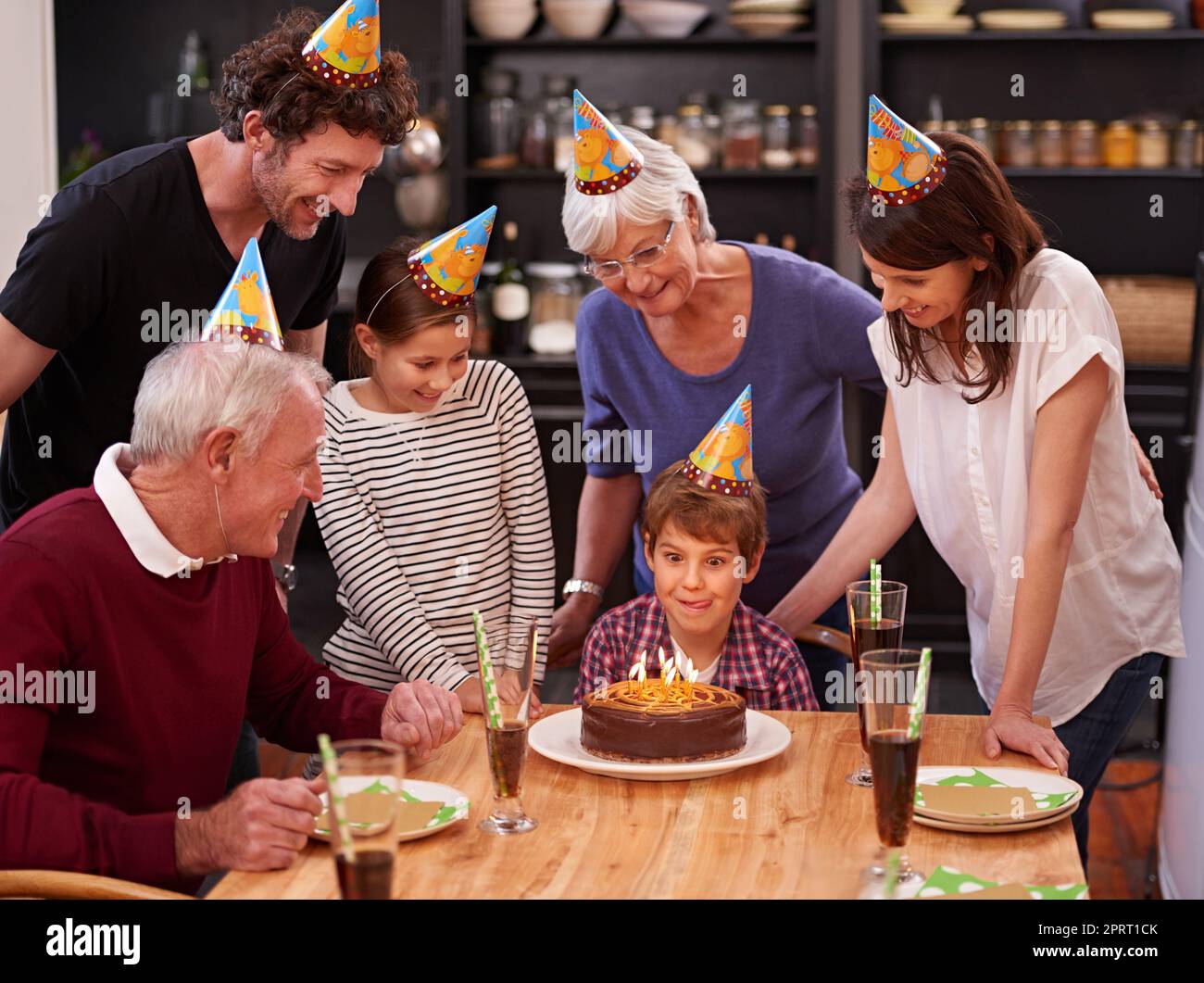 Zeit, Ihre Kerzen auszublasen. Ein glücklicher kleiner Junge feiert seinen Geburtstag mit seiner Familie. Stockfoto