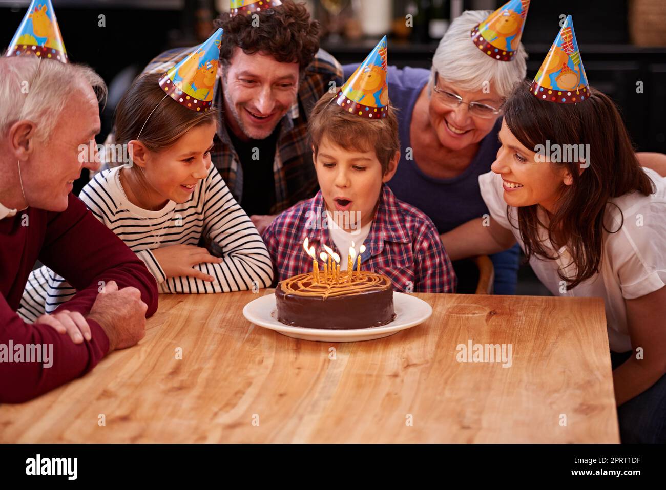 Ich kann sie sofort ausblasen. Ein glücklicher kleiner Junge, der seinen Geburtstag mit seiner Familie feiert. Stockfoto