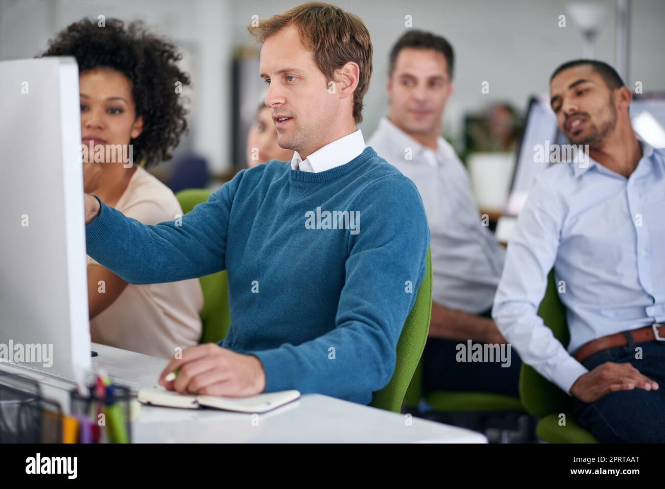 Eine Gruppe kreativer Geschäftsleute, die im Büro an einem Computer arbeiten. Stockfoto