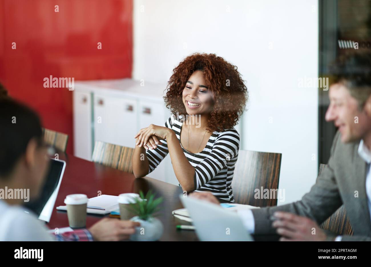 Morgendliche Meeting-Zeit. Kollegen sitzen an einem Sitzungstisch und reden. Stockfoto