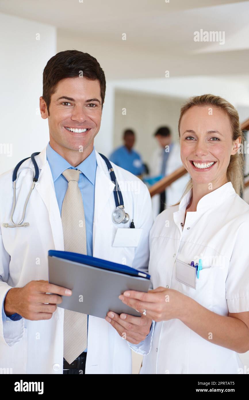 Sie lieben, was sie tun. Porträt eines männlichen Arztes und einer Krankenschwester, die mit Krankenakten steht. Stockfoto