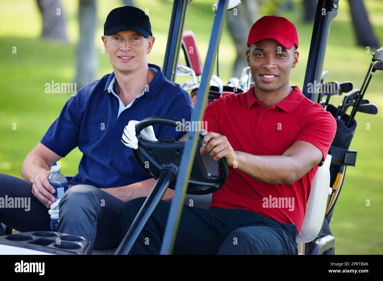 Auf eine Fahrt mit Freunden. Porträt von zwei Männern, die auf einem Golfplatz einen Wagen fahren. Stockfoto